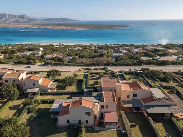 A coastal residential area with houses, a road, and a view of the sea.