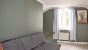 A room with a grey sofa, a window with white curtains, and a painting on the wall. - 2 bedroom nice home in åsenhöga (Åsenhöga)