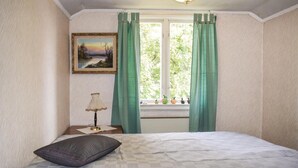 A bedroom with a bed, a nightstand with a lamp, a framed picture on the wall, and a window with curtains. - 2 bedroom nice home in åsenhöga (Åsenhöga)