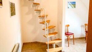 A spiral staircase with wooden steps and metal railings, leading to a landing with a red chair. - Vacation apartment Ostseestern 19O-2 bedrooms up to max. 4 pers. + 2 baby - Holiday home (Trassenheide)
