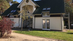 A two-story house with a sloped roof, a small porch, and a staircase leading to an upper level. - Vacation apartment Ostseestern 19O-2 bedrooms up to max. 4 pers. + 2 baby - Holiday home (Trassenheide)