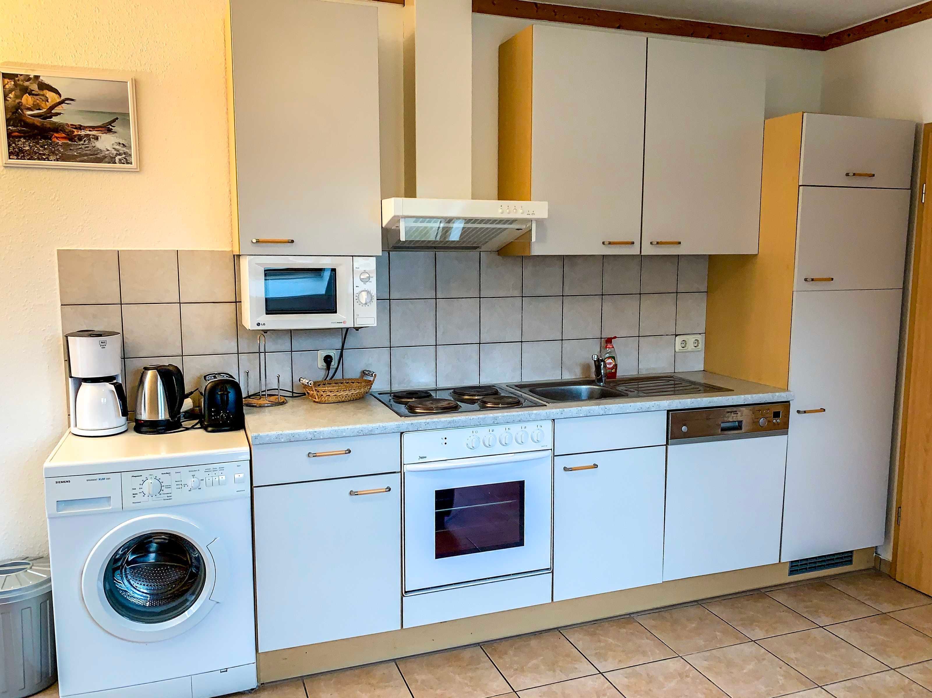 Une cuisine compacte équipée d’un lave-linge, d’un four à micro-ondes, d’une cuisinière et d’un four.