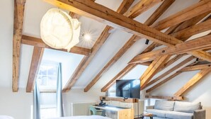 A bedroom with a wooden ceiling, a bed, a desk, and a sofa. - Romantik Hotel Stern (Chur)