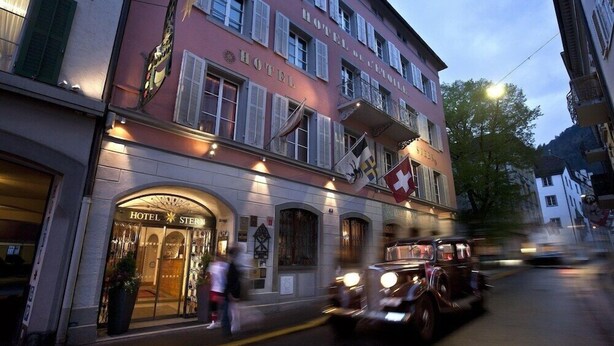 A historic hotel with a classic facade, multiple balconies, and a Swiss flag. - Romantik Hotel Stern (Chur)