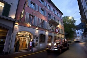 Een historisch hotel met een klassiek gevelontwerp, meerdere balkons en een Zwitserse vlag.