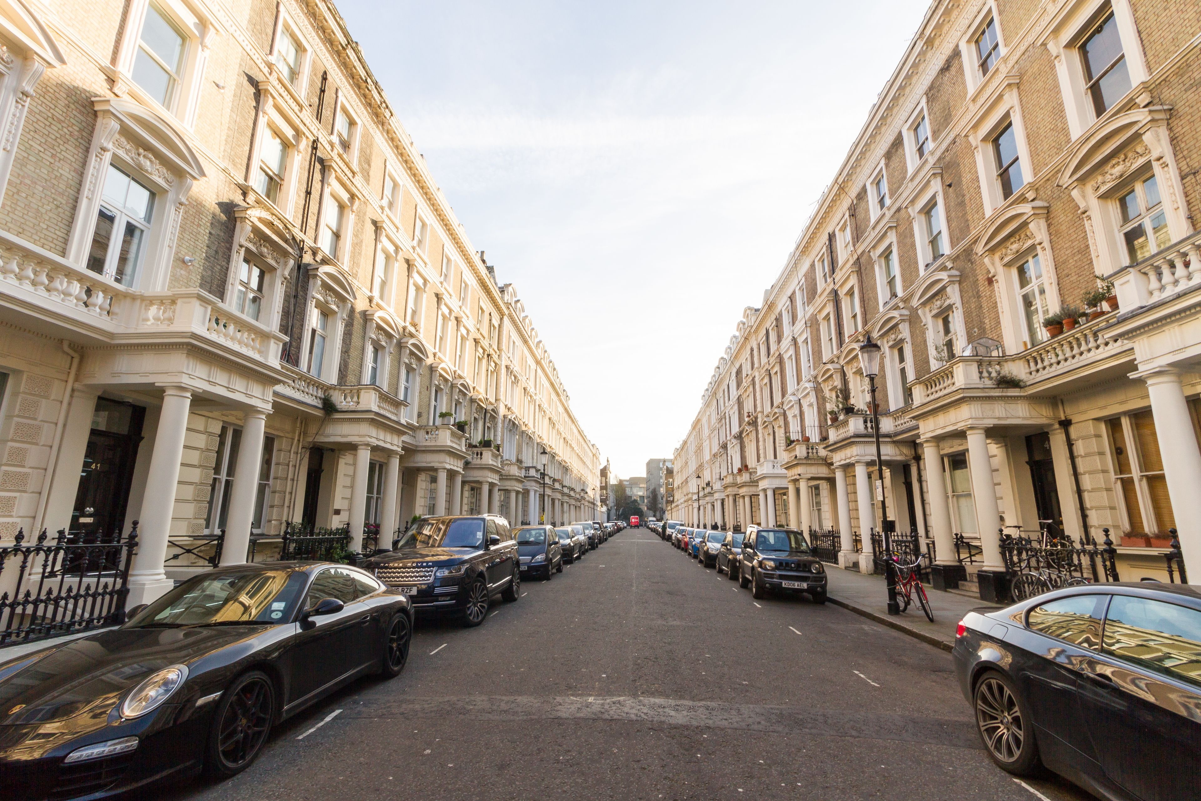 A street lined with parked cars and classic buildings.