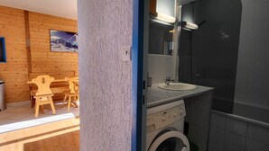 Un baño pequeño con lavadora, lavamanos y espejo.