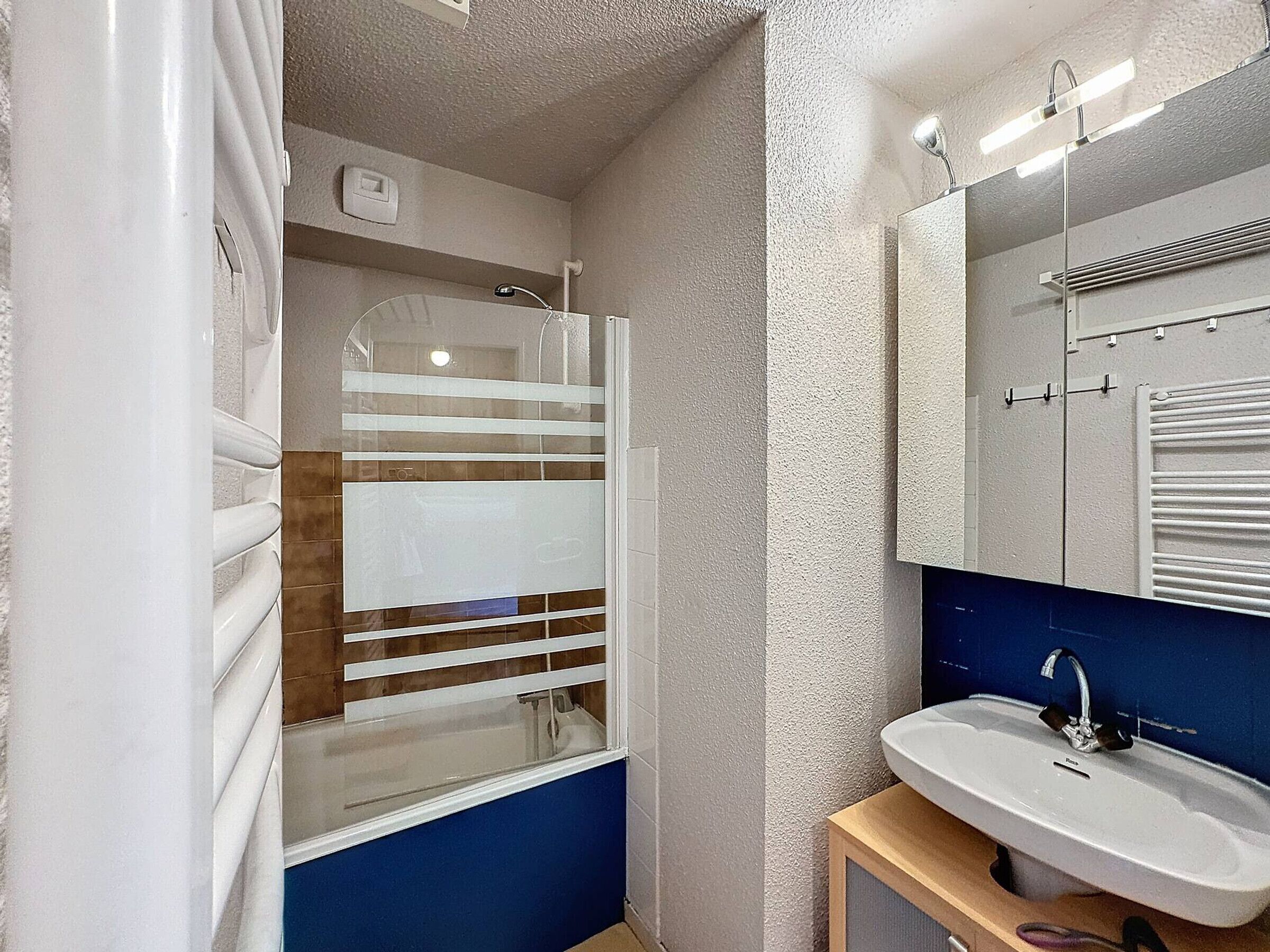 A bathroom with a shower, a sink, and a mirror.
