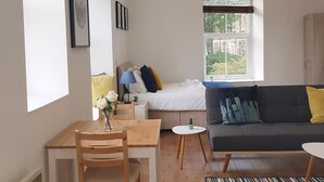 Une pièce moderne et bien éclairée, comprenant une table à manger, un canapé et un lit.