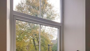 Un siège près d’une fenêtre donnant sur un jardin et des arbres.