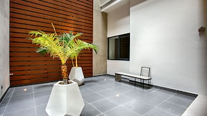 Un hall d’entrée moderne avec une grande plante en pot, un banc et un panneau fixé au mur.