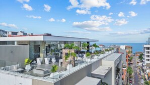 Une terrasse sur le toit, dotée de mobilier moderne, d’une piscine et offrant une vue sur la mer.