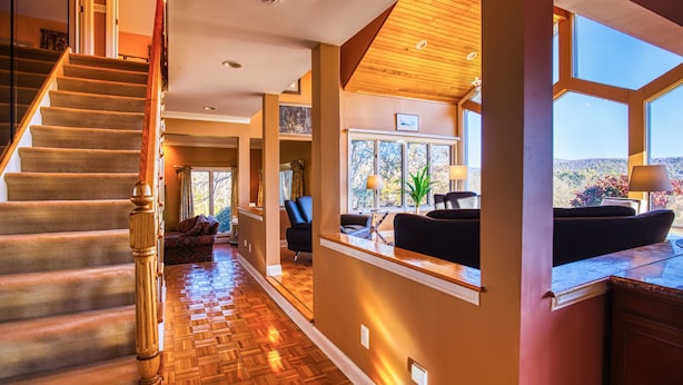 Un interior espacioso con una escalera de madera, una sala de estar con vistas y un gran ventanal.