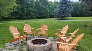 Un hogar con cuatro sillas Adirondack dispuestas alrededor en un patio de piedra.