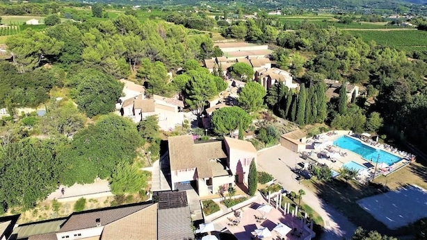 Vista aèria d'un complex turístic amb piscina, envoltat de vegetació exuberanta i un paisatge amb turons.