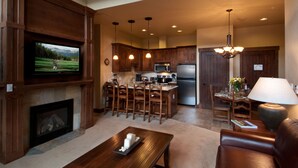 A modern kitchen with wooden cabinets, a central island, and a dining area with a chandelier. - Ski in/Ski out room on Peak 7 for Presidents Day Week! (Breckenridge)