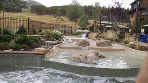 A hot spring area with a tiled pool, rocks, and a waterfall. - Ski in/Ski out room on Peak 7 for Presidents Day Week! (Breckenridge)