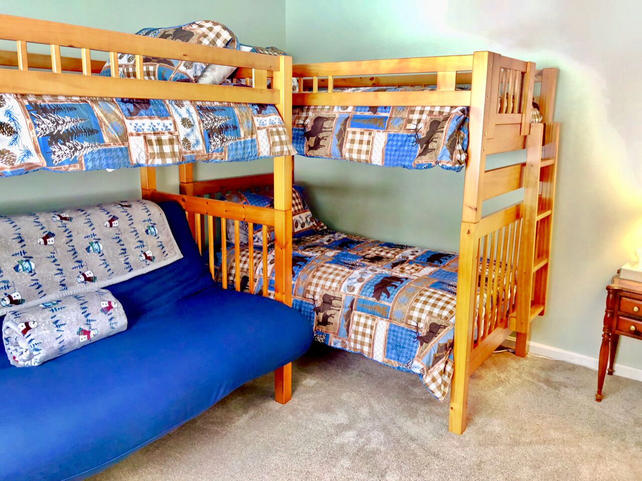 Dormitorio con literas, un colchón azul y ropa de cama estampada.