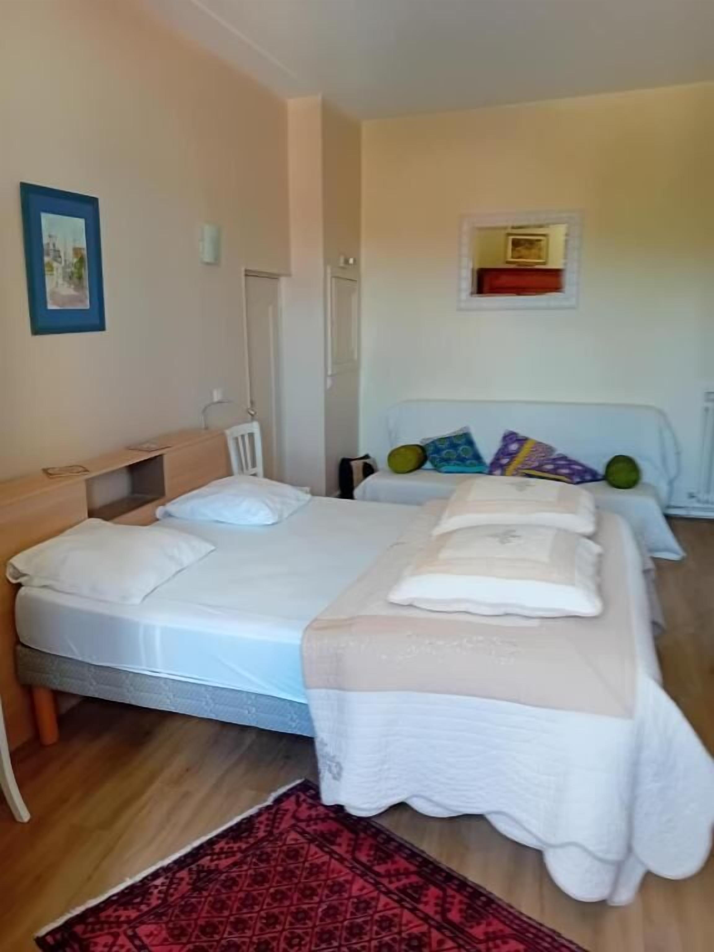 Un dormitorio con cama, mesitas de noche, un espejo y una estantería en la pared.