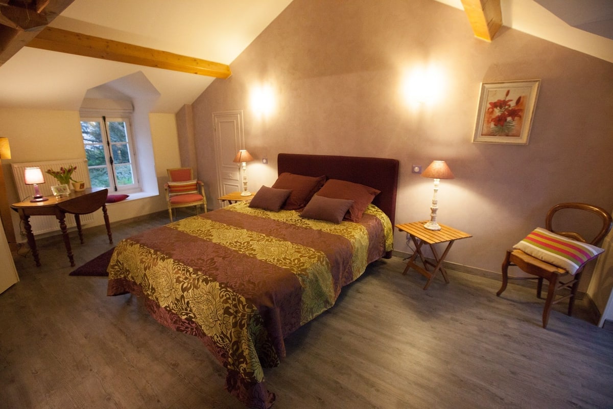 Une chambre à coucher avec un grand lit, deux tables de chevet, une chaise, une fenêtre et un tableau au mur.