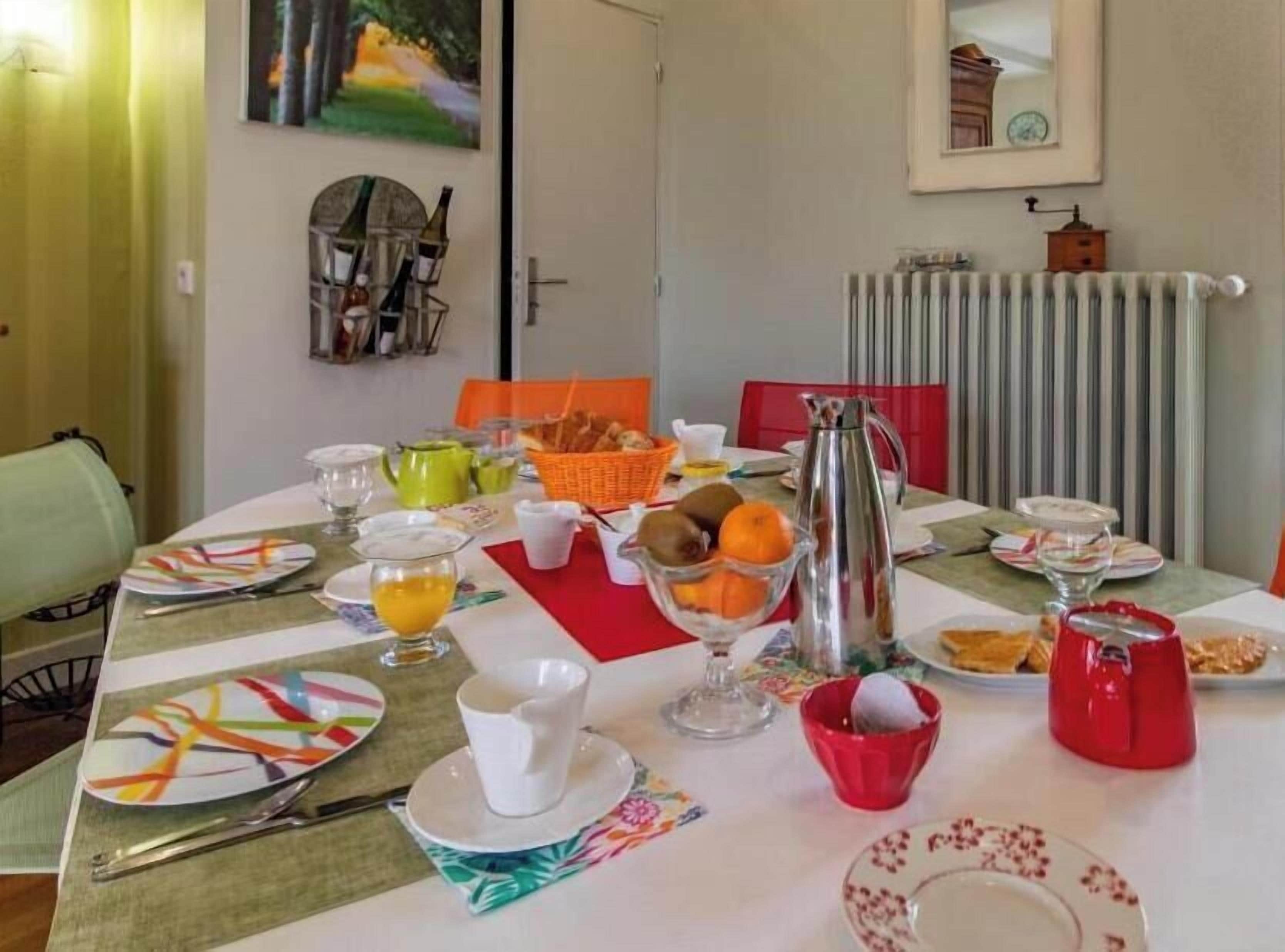 A dining table set with plates, cups, and a fruit bowl.
