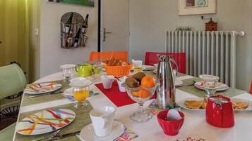 A dining table set with plates, cups, and a fruit bowl.