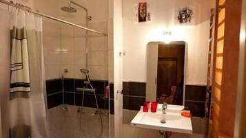Un baño con ducha, lavabo y espejo.