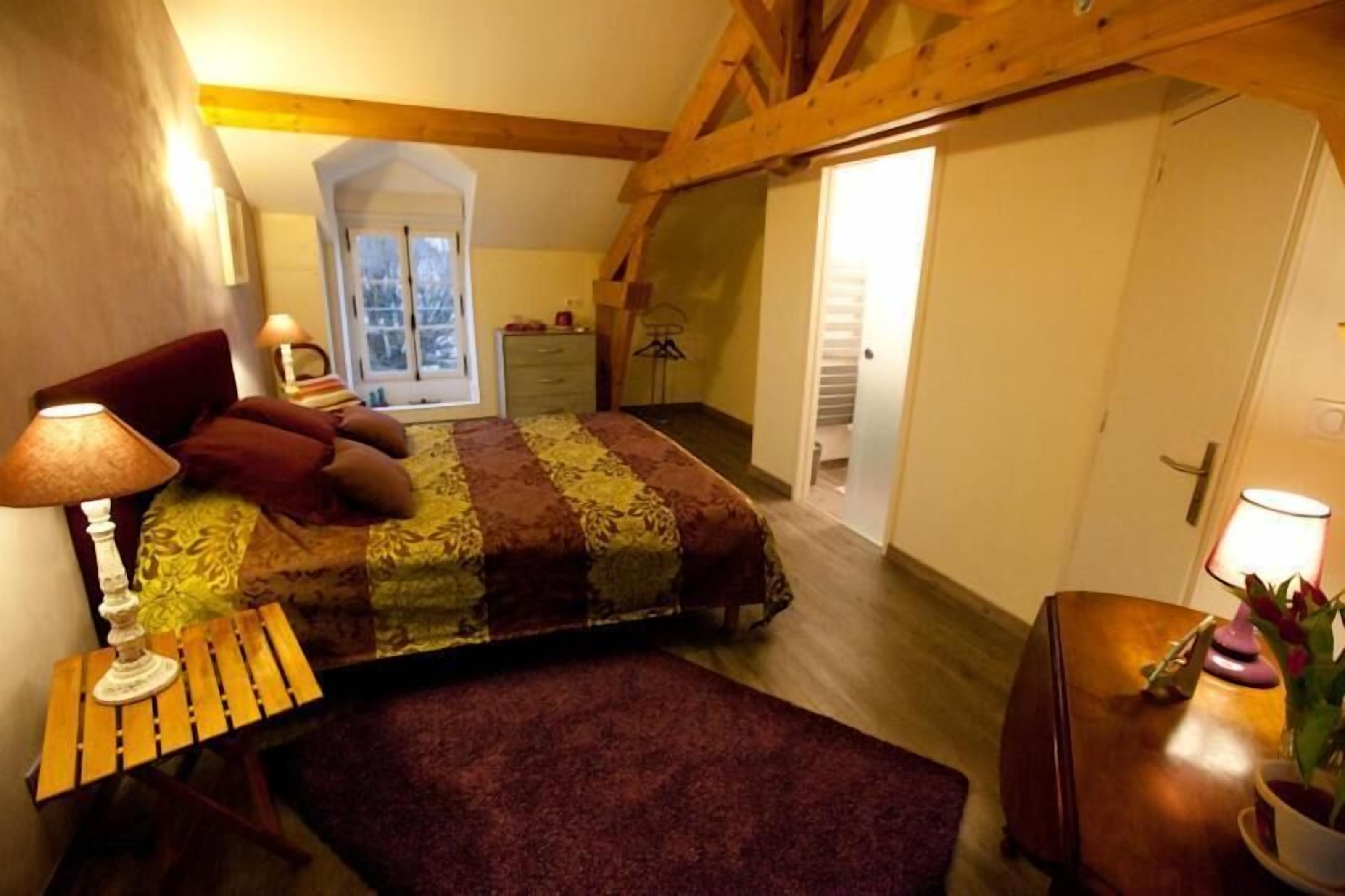 Une chambre à coucher avec un lit, une table de chevet, une lampe et une fenêtre.