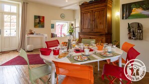 Un comedor con una mesa redonda dispuesta para el desayuno, rodeada de sillas, y un mueble de madera en la parte superior.