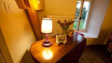 A wooden table with a lamp, a vase with red flowers, and a framed picture.