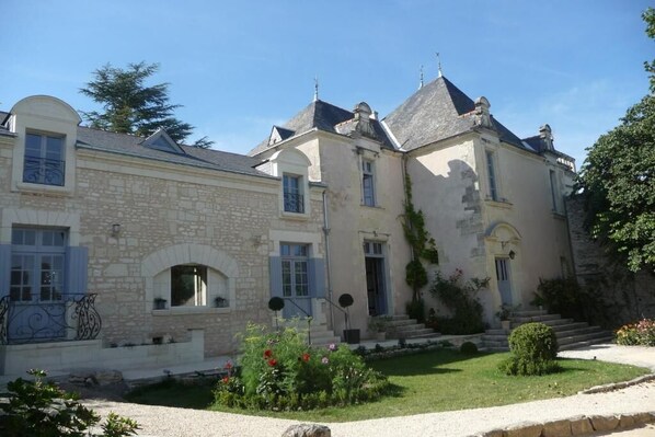 A two-story stone house with a garden in front.