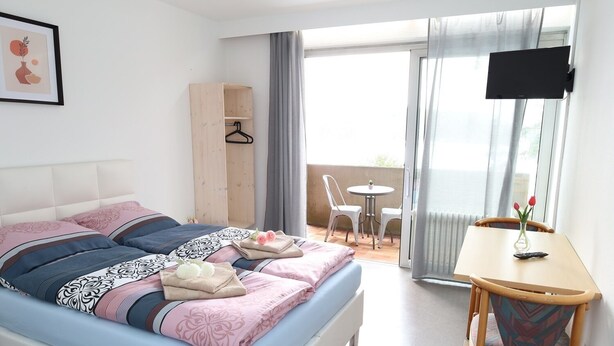 A bedroom with a bed, bedside table, and a view of the balcony. - Pension Highway 3 Sennestadt-Bielefeld (Bielefeld)