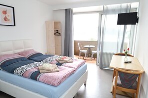Un dormitorio con cama, mesita de noche y vistas al balcón.