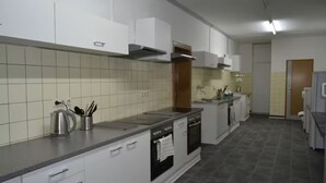 A modern kitchen with white cabinets, a stainless steel range, and a tiled backsplash. - Pension Highway 3 Sennestadt-Bielefeld (Bielefeld)