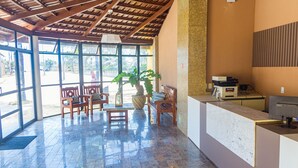 A reception area with a wooden ceiling, large windows, a reception desk, and a potted plant. - Kalamari Beach Hotel (Aquiraz)