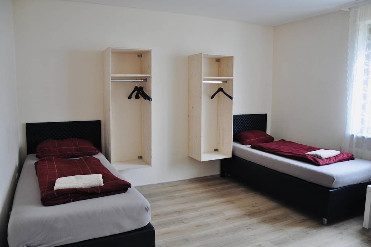 Ein Zimmer mit zwei Betten, einem Schrank und einem fenster mit Vorhängen.