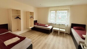 A hotel room with two beds, a wardrobe, a window with lace curtains, and a wooden floor. - Pension Highway Bünde (Buende)