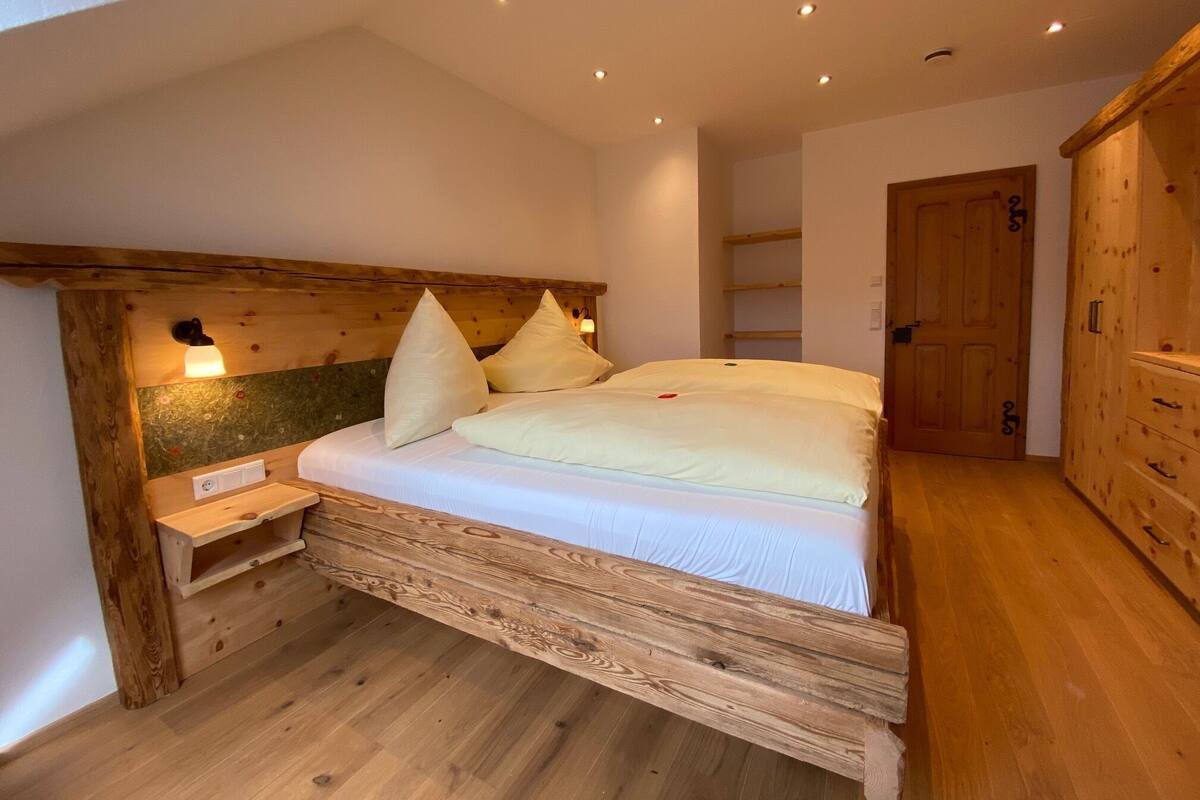 A wooden bed with a headboard, a bedside table, and a nightstand.