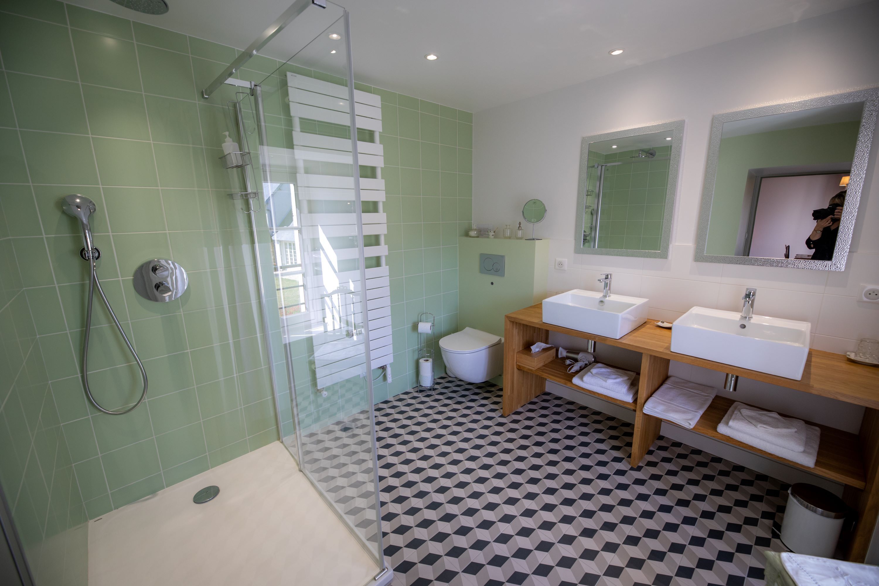 A modern bathroom with a shower, two sinks, and a toilet.