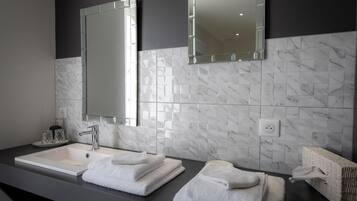 A modern bathroom with a white marble sink, two mirrors, and neatly folded towels.