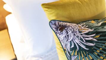 A close-up of a bed with a white pillow and a yellow pillow with a floral design.
