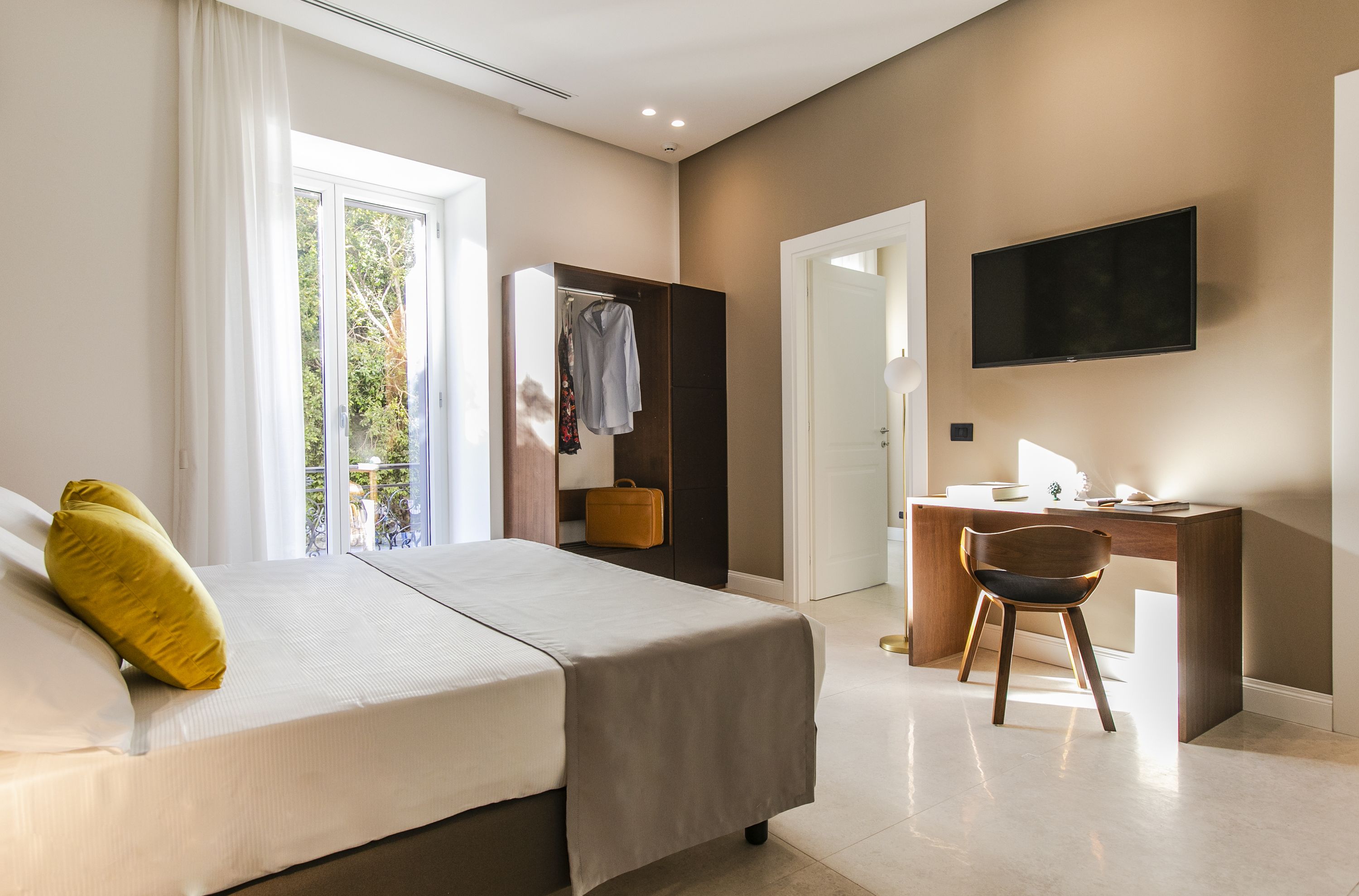 Ein modernes Hotelzimmer mit Bett, Schreibtisch und Fernseher.