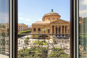Vista de un edificio histórico con cúpula y arquitectura clásica, visible desde un balcón con barandillas de metal ornamentado.