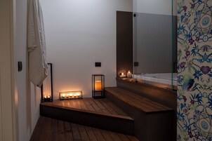 Un bagno moderno con pavimento in legno, uno specchio e candele.