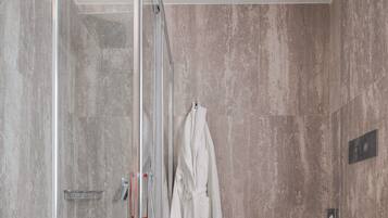Un baño moderno con ducha de vidrio, una bañera blanca y un inodoro.