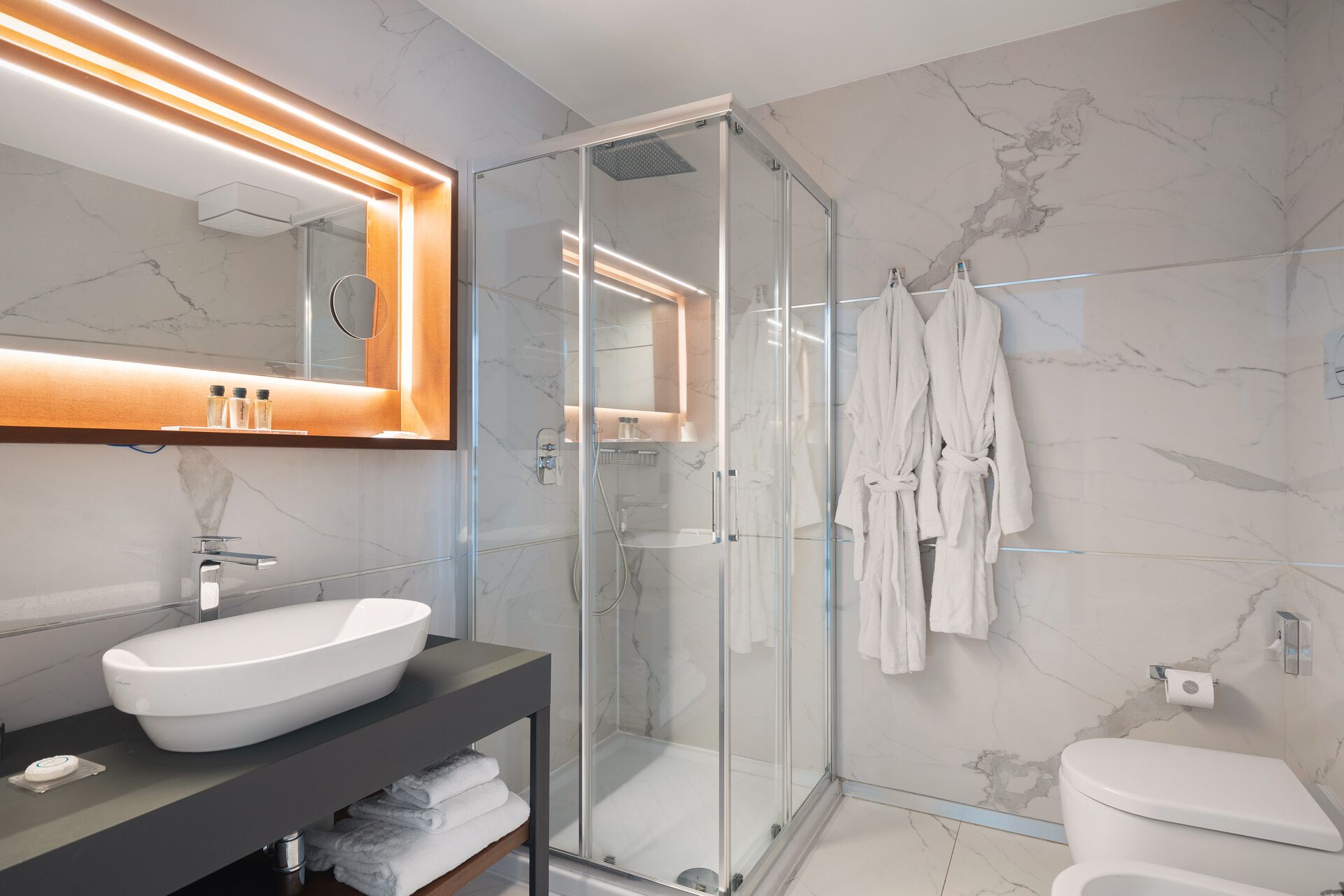 A modern bathroom with a glass-enclosed shower, a large mirror, and a white sink.