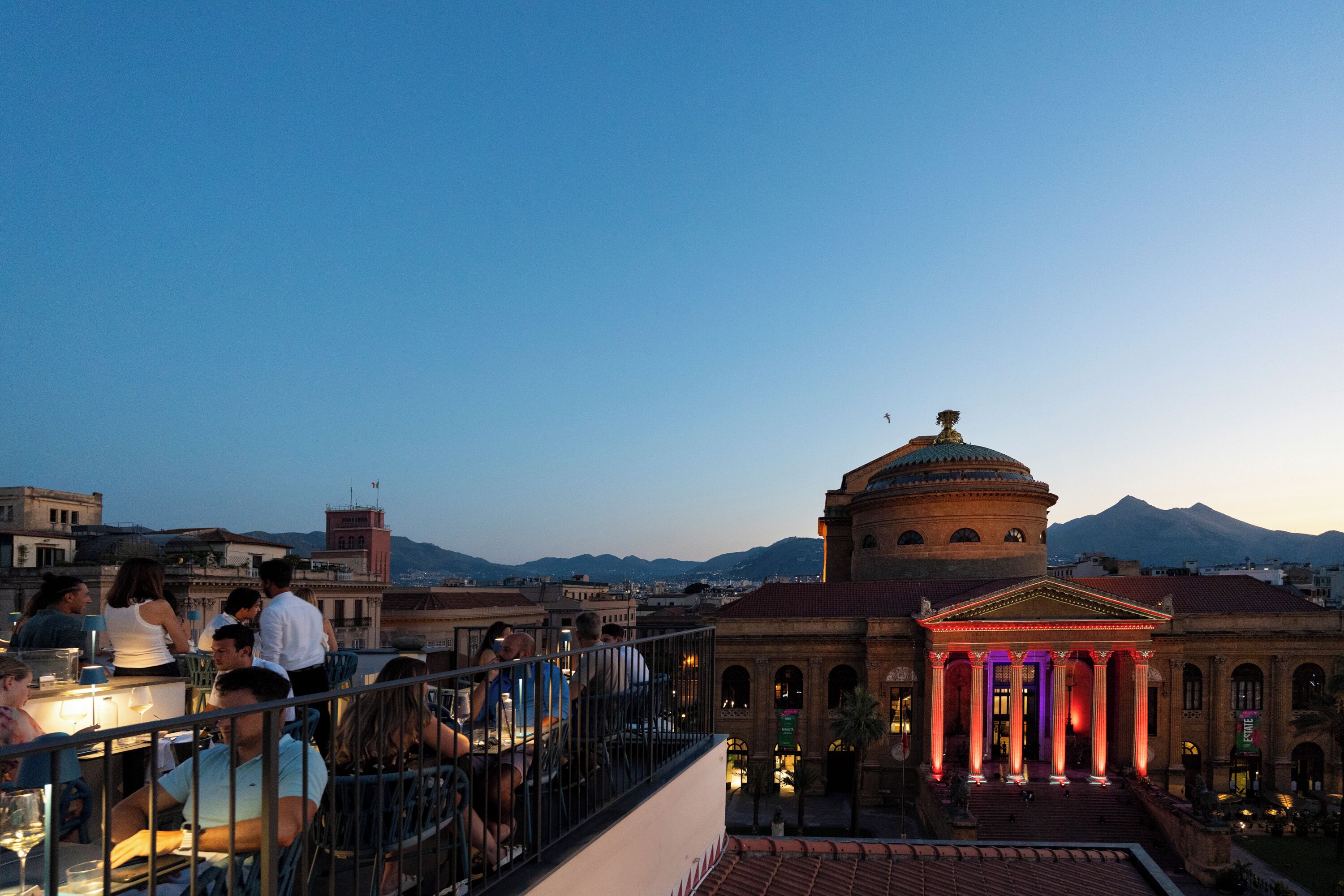 Una terraza en la azotea con vistas a un edificio clásico y montañas al fondo.