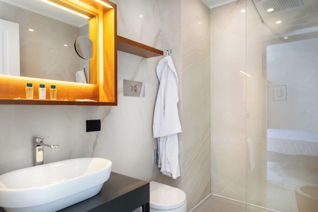 Une salle de bain moderne avec un grand lavabo ovale, un miroir, un porte-serviettes et un espace douche.