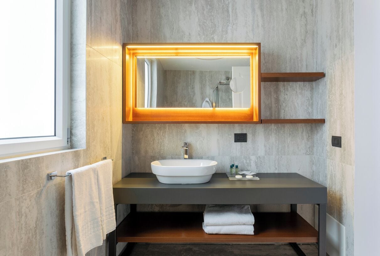 Een moderne badkamer met een grote spiegel, een wit wastafelmeubel en een handdoekhouder.