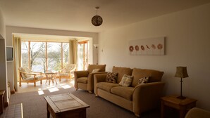 Una sala de estar con sofá, sillones, una mesa de centro y televisor.